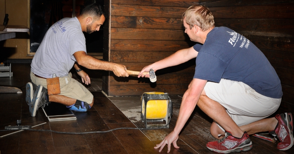 Flooring installers working to install new flooring with precise alignment and professional tools