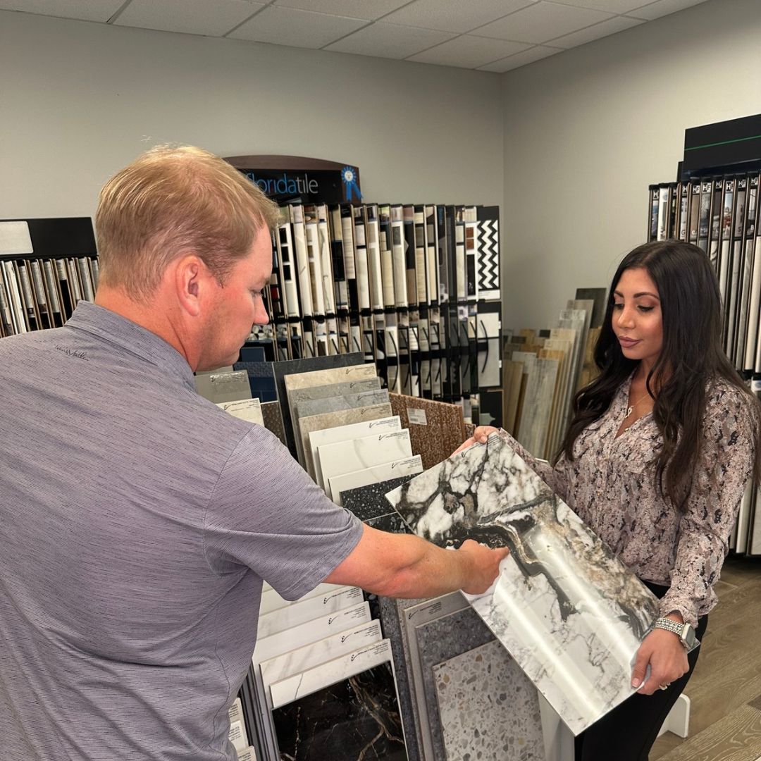 Floor de Lis owner Mark Hughes and a woman comparing a marble-look tile sample in the showroom.